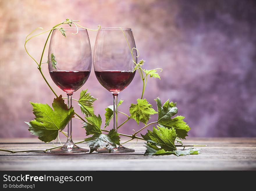 Heart-shaped leaves around two glasses of red wine. Heart-shaped leaves around two glasses of red wine