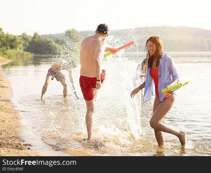 Happy People With Water Guns Have Fun On The Beach