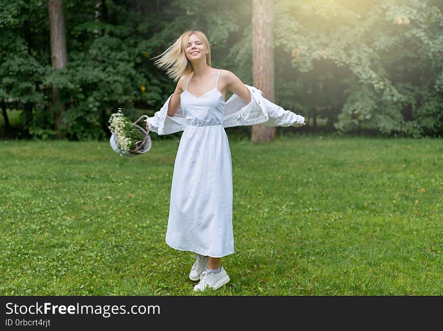 Beautiful Young Woman Outdoors holding basket with daisies. Enjoy Nature. Healthy Smiling Girl in Green Grass. Copyspace