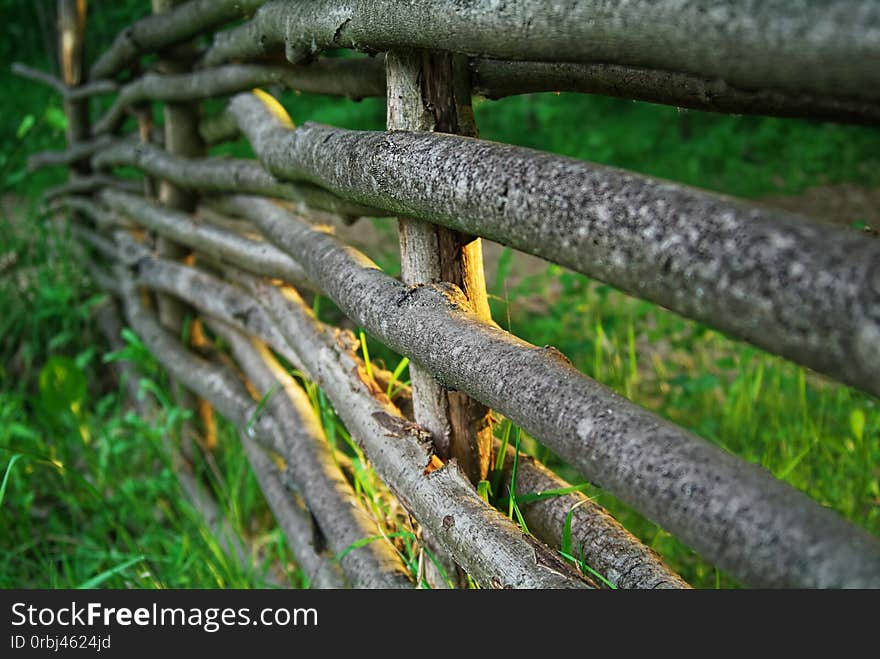 A Fence Woven From Tree Branches In The Evening