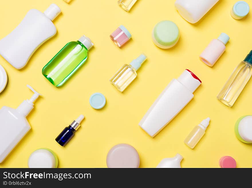 Top view of different cosmetic bottles and container for cosmetics on yellow background. Flat lay composition with copy space