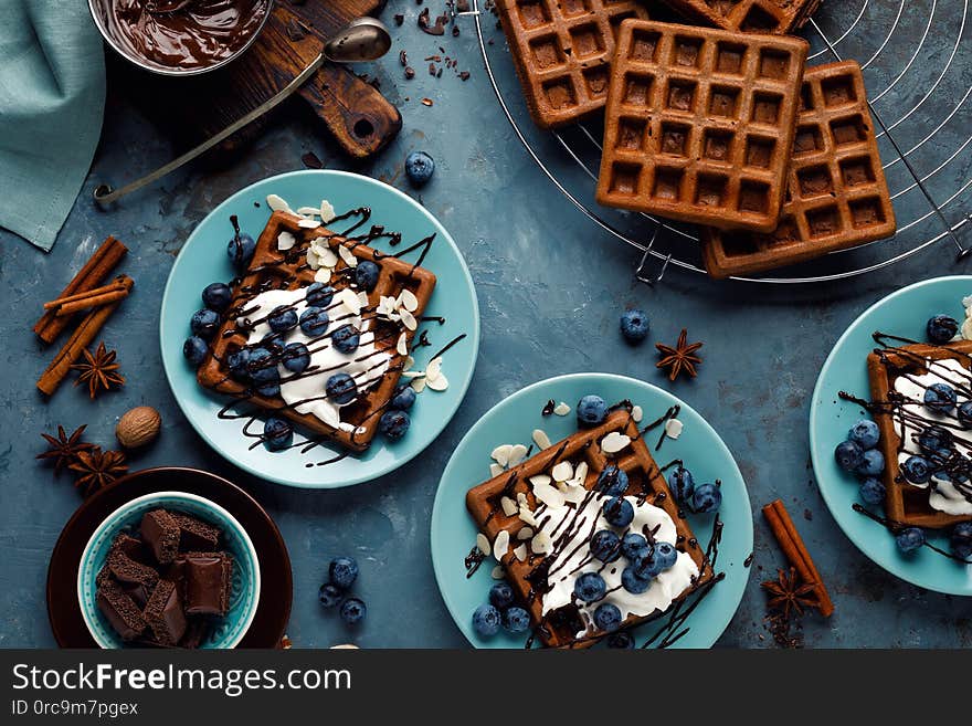 Chocolate belgian waffles with ice cream and fresh blueberry on blue background, top view