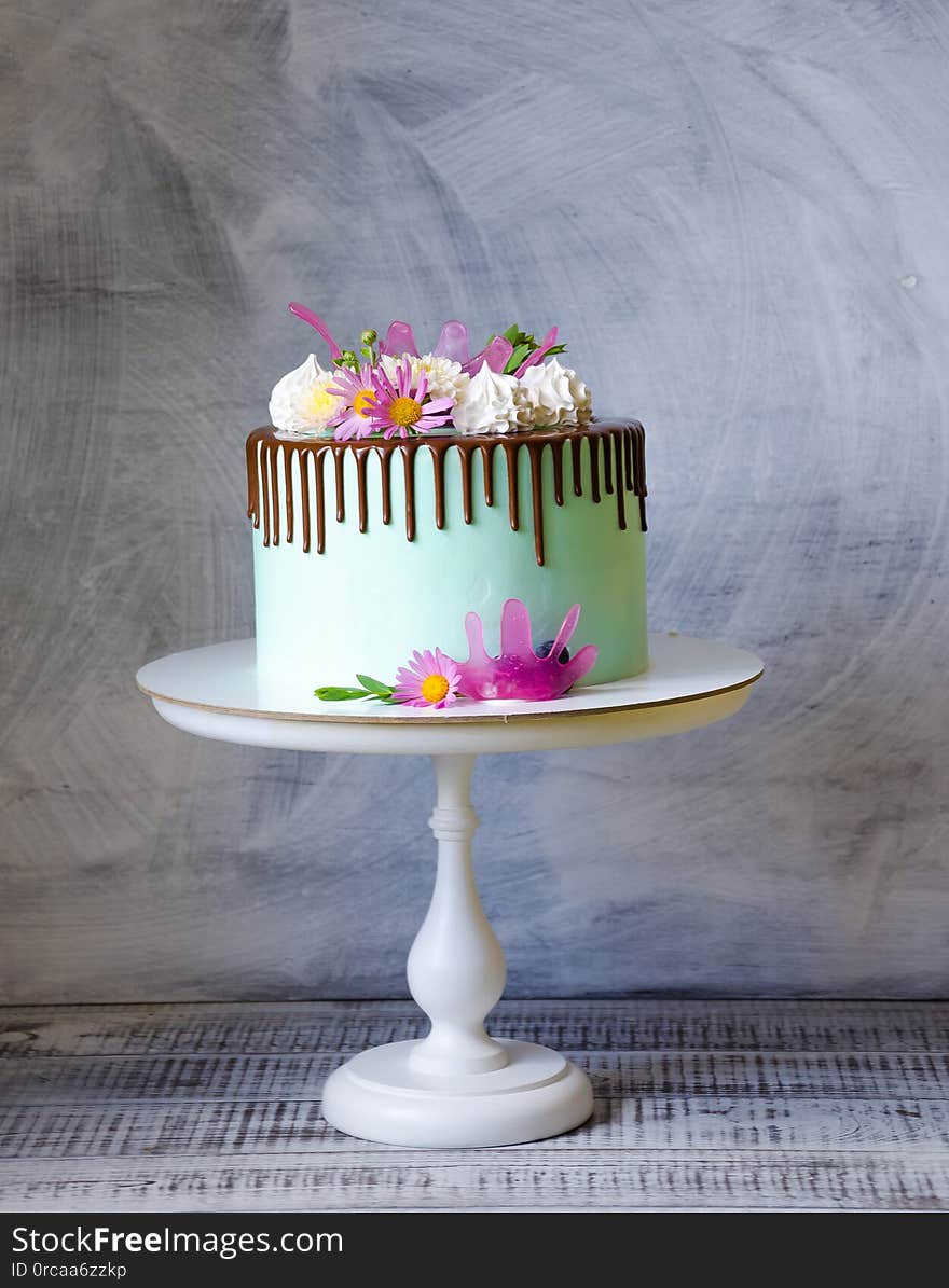 Tasty chocolate drip cake decorated with zephyr and flowers