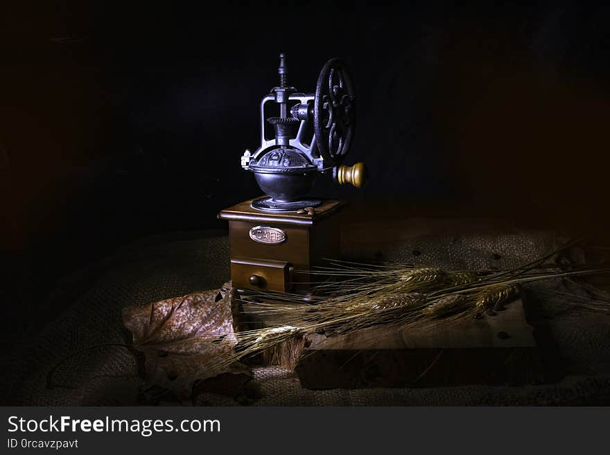 Stylized vintage coffee grinder, dry leaves and ears of wheat on a burlap-covered wooden table. Stylized vintage coffee grinder, dry leaves and ears of wheat on a burlap-covered wooden table