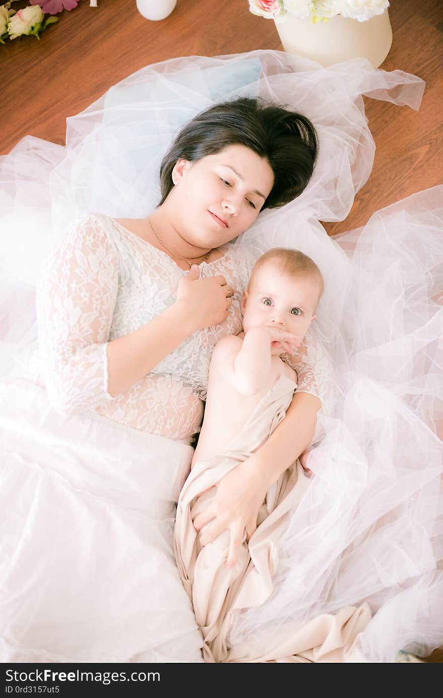 Young mom with a baby in her arms in the bright boudoir bedroom