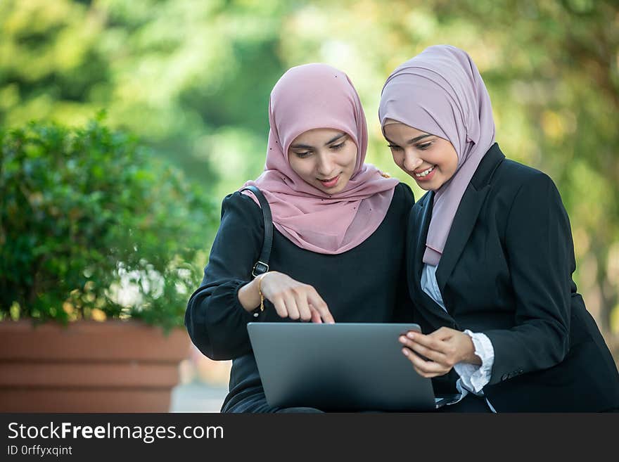 Muslim Female Friends looking at a laptop together. Outdoor shoot.