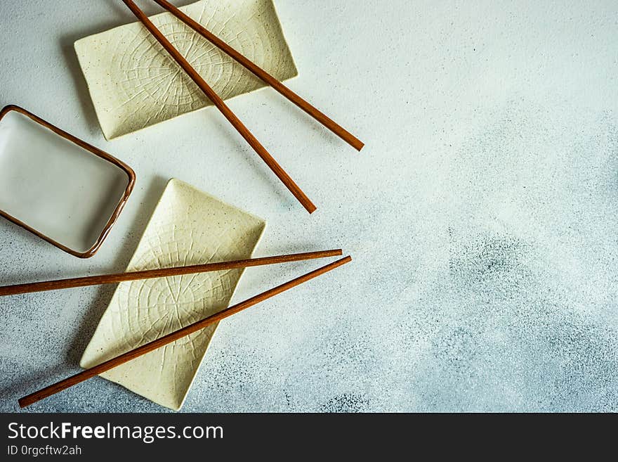 Asian table setting with ceramic bowl and wooden chopsticks on stone background with copy space. Asian table setting with ceramic bowl and wooden chopsticks on stone background with copy space