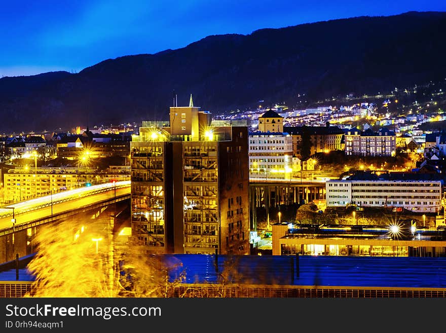 Bergen, Norway. View of Bergen, Norway at night. Colorful cloudy blue sky over the mountains with illuminated roads and car traffic
