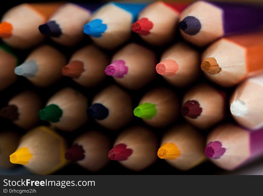 Wooden pencils in all colors seen from the sheet of pencils. Colored pencils stacked with a black background. Colors. Back to