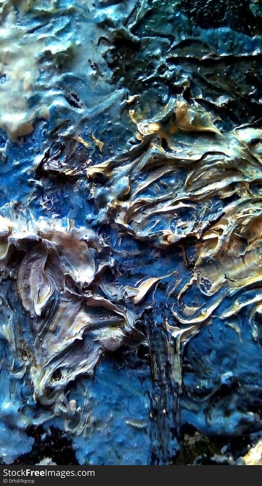 Close-up of smears of oil paint on the surface of the canvas. Blue, green, light spots on a dark background.