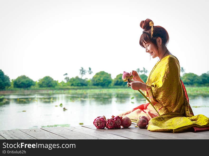 A Beautiful Woman Wearing Traditional Thai Clothes Folds A Lotus Flower.