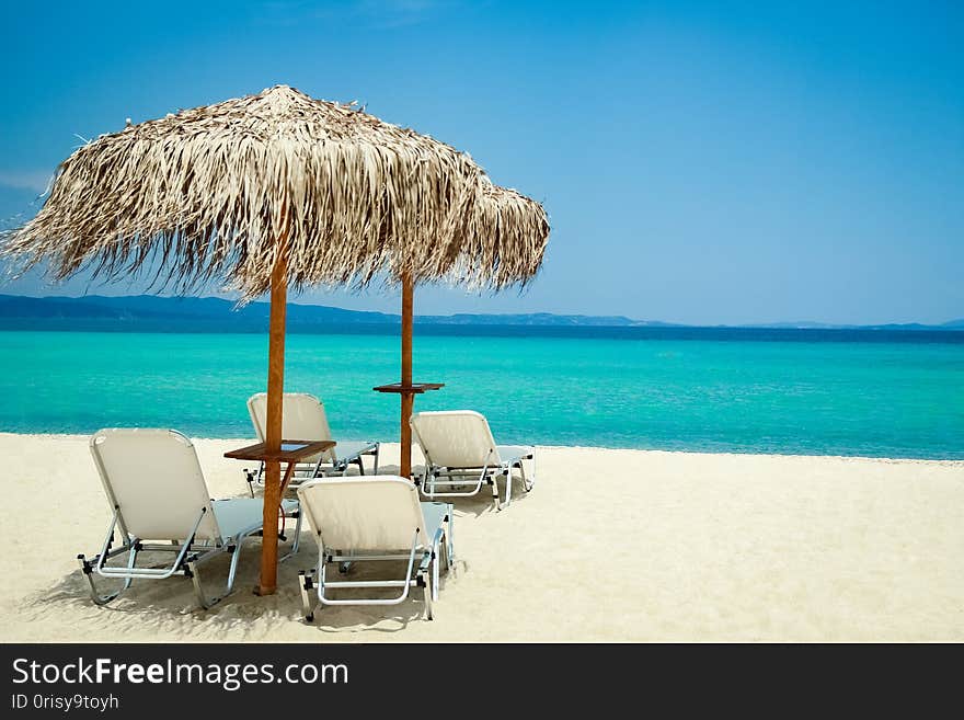 Beautiful beach chairs near the seashore of Greece on the nature background