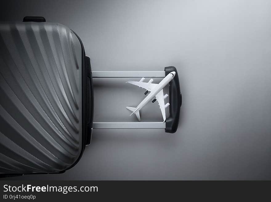 Flat lay grey suitcase with mini airplane on grey background. travel concept - Image