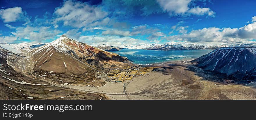 Aerial view of scenic town on island with mountain peaks during sunny summer day. Aerial view of scenic town on island with mountain peaks during sunny summer day