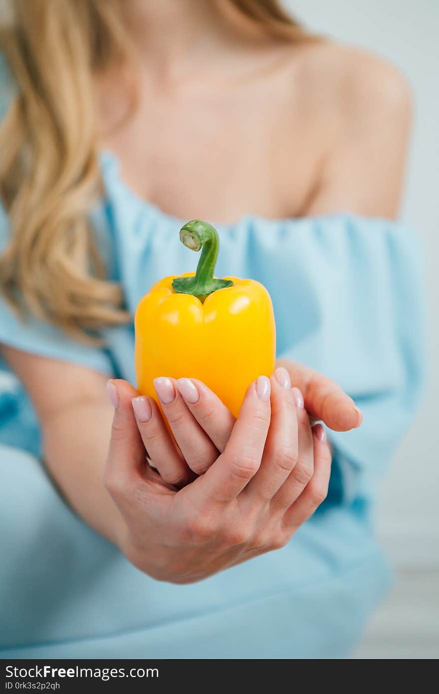 Young beautiful girl holding fresh yellow pepper on white background. The concept of healthy eating. Toning