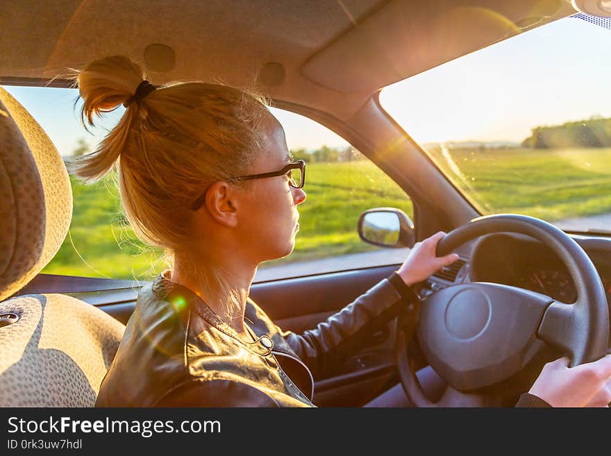 Casual caucasian woman driving a passenger car for a journey in countryside.