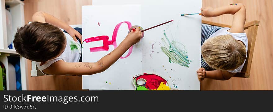 Two toddler kids painting with colors