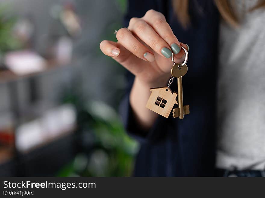 Concept of renting an apartment. House key in womans hands. Young woman. Modern light lobby interior. Real estate