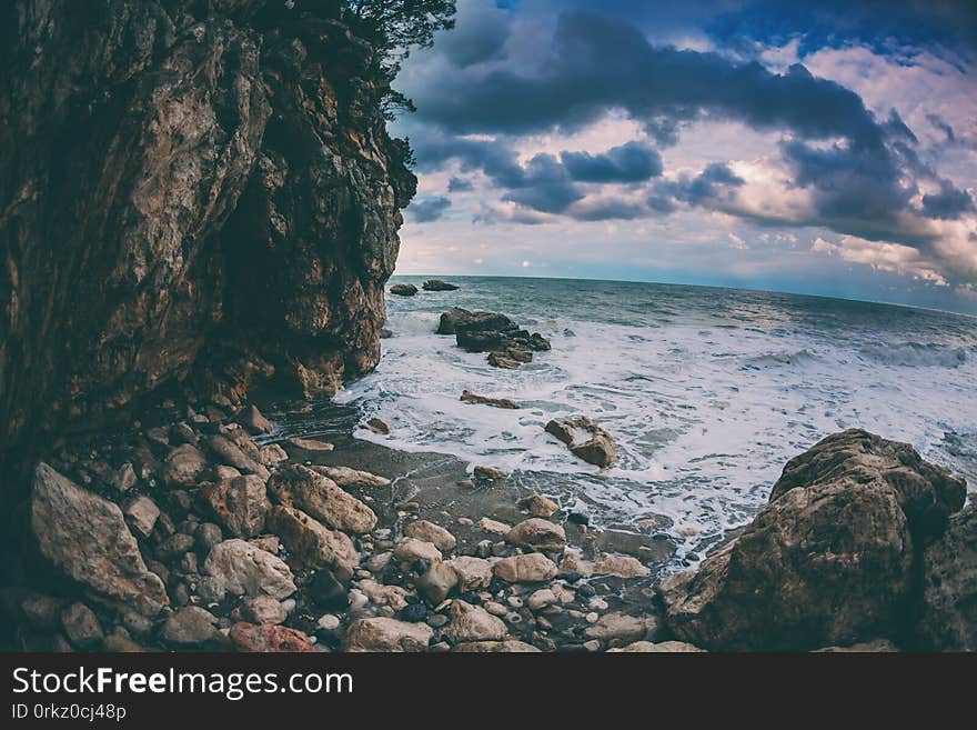 Rocky seashore. Strong waves and wind. Storm. Ocean against the background of the cloudy sky. Big stones on the seashore