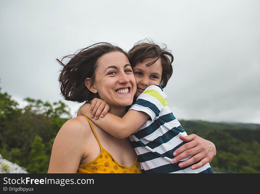 The boy hugs mom. Woman rests with her son in nature. The child kisses mom. Portrait of a mother and baby