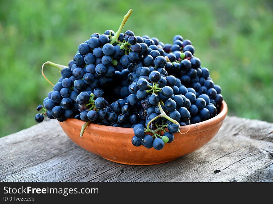 Black Grapes In A Ceramic Plate On An Old Board In The Garden.