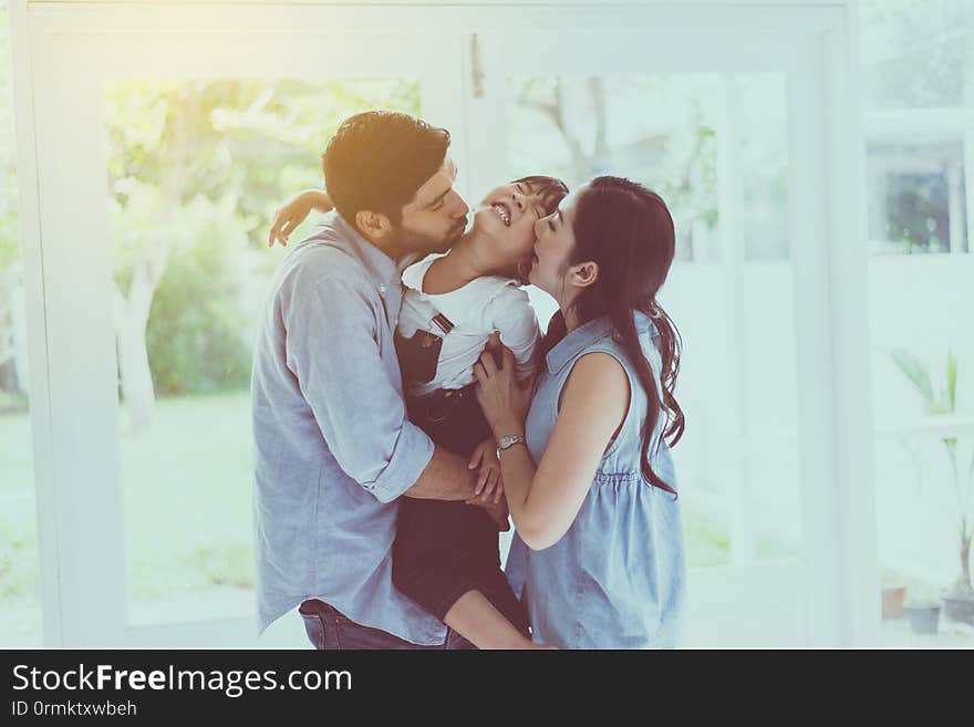 Father and mother kiss cheek daughter child girl playing,Laughing and funny together at home,Happy loving family