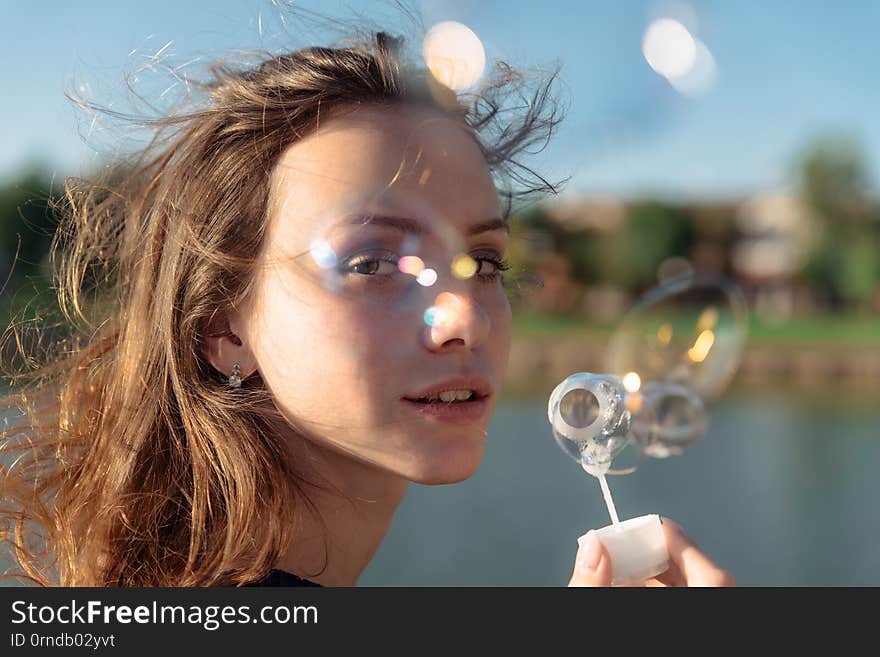 Gorgeous young brunette girl blowing soap bubbles in sunlit park, portrait, people, attractive, joyful, pretty, lifestyle, fun, wand, person, outdoors, cheerful, happy, woman, happiness, leisure, beautiful, air, childish, lips, mouth, smile, shampoo, recreational, carefree. Gorgeous young brunette girl blowing soap bubbles in sunlit park, portrait, people, attractive, joyful, pretty, lifestyle, fun, wand, person, outdoors, cheerful, happy, woman, happiness, leisure, beautiful, air, childish, lips, mouth, smile, shampoo, recreational, carefree