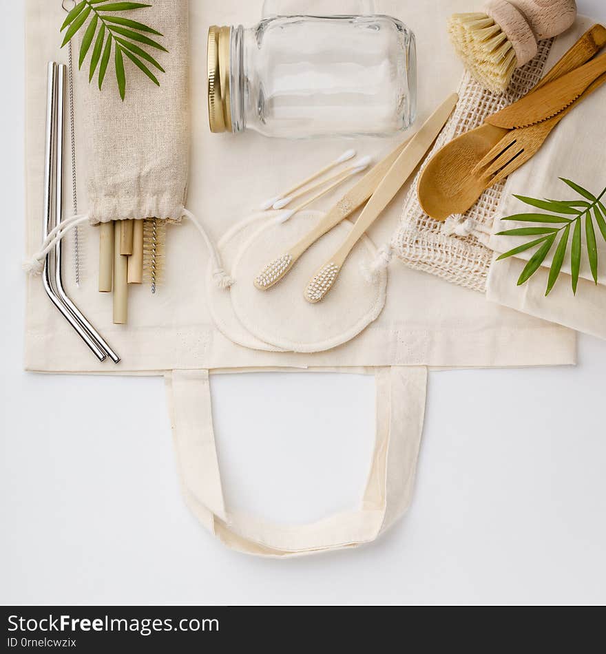 Natural color eco bags, reusable metal and bamboo straws, glass jars, wooden knifes and forks, zero waste cleaning and beauty products, flat lay. Natural color eco bags, reusable metal and bamboo straws, glass jars, wooden knifes and forks, zero waste cleaning and beauty products, flat lay