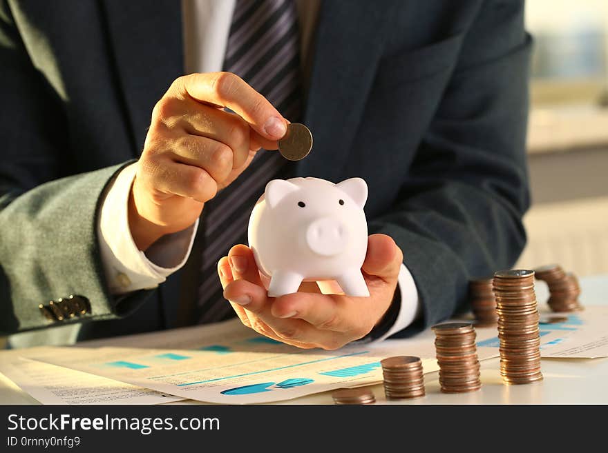 Hand Businessman Putting Pin Money Into Pig