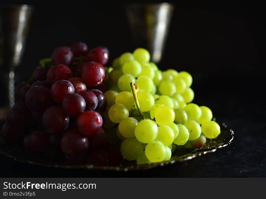 A traditional Mediterranean platter with grapes and wine on black background. A traditional Mediterranean platter with grapes and wine on black background.