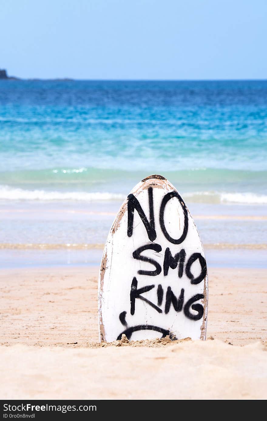 No Smoking warning sign on white surfboard at the beach in summer, concept of sea environmantal protection design, copy space