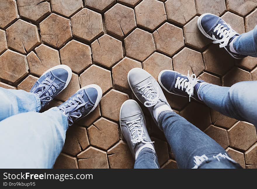 Three pairs of woman’s and child’s legs; wooden background; top view