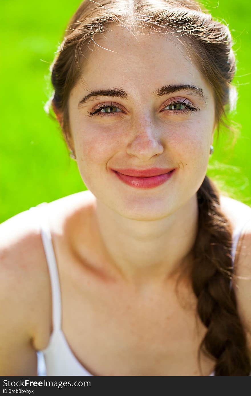 Closeup portrait of a young beautiful brunette woman in on summer park background