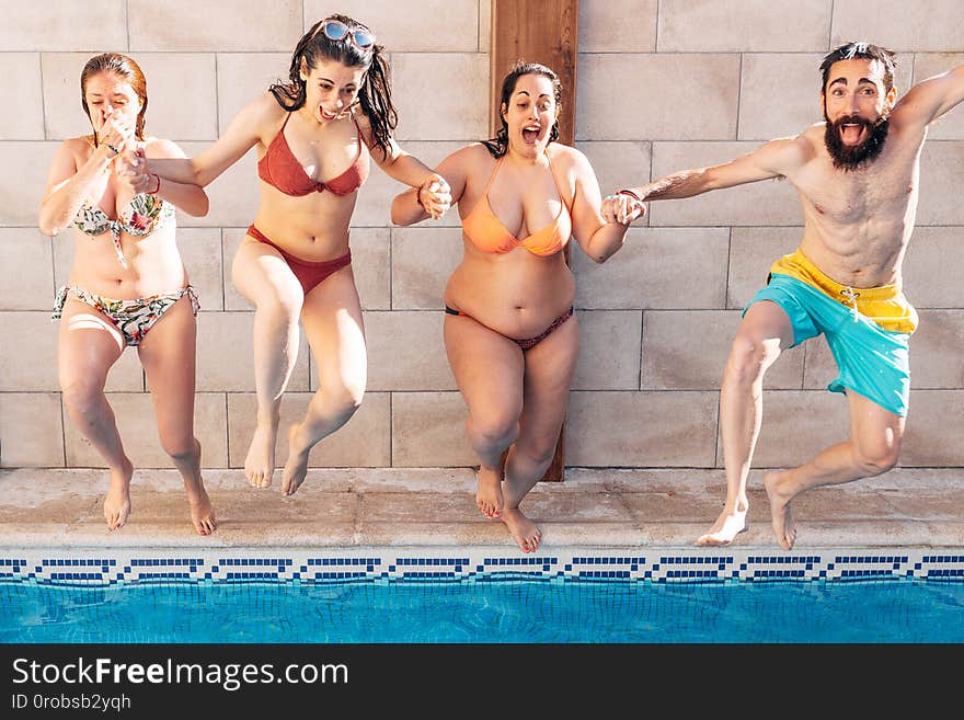 Group of happy friends holding hands and jumping in pool. Young diverse culture people having fun in vacation. Holiday and