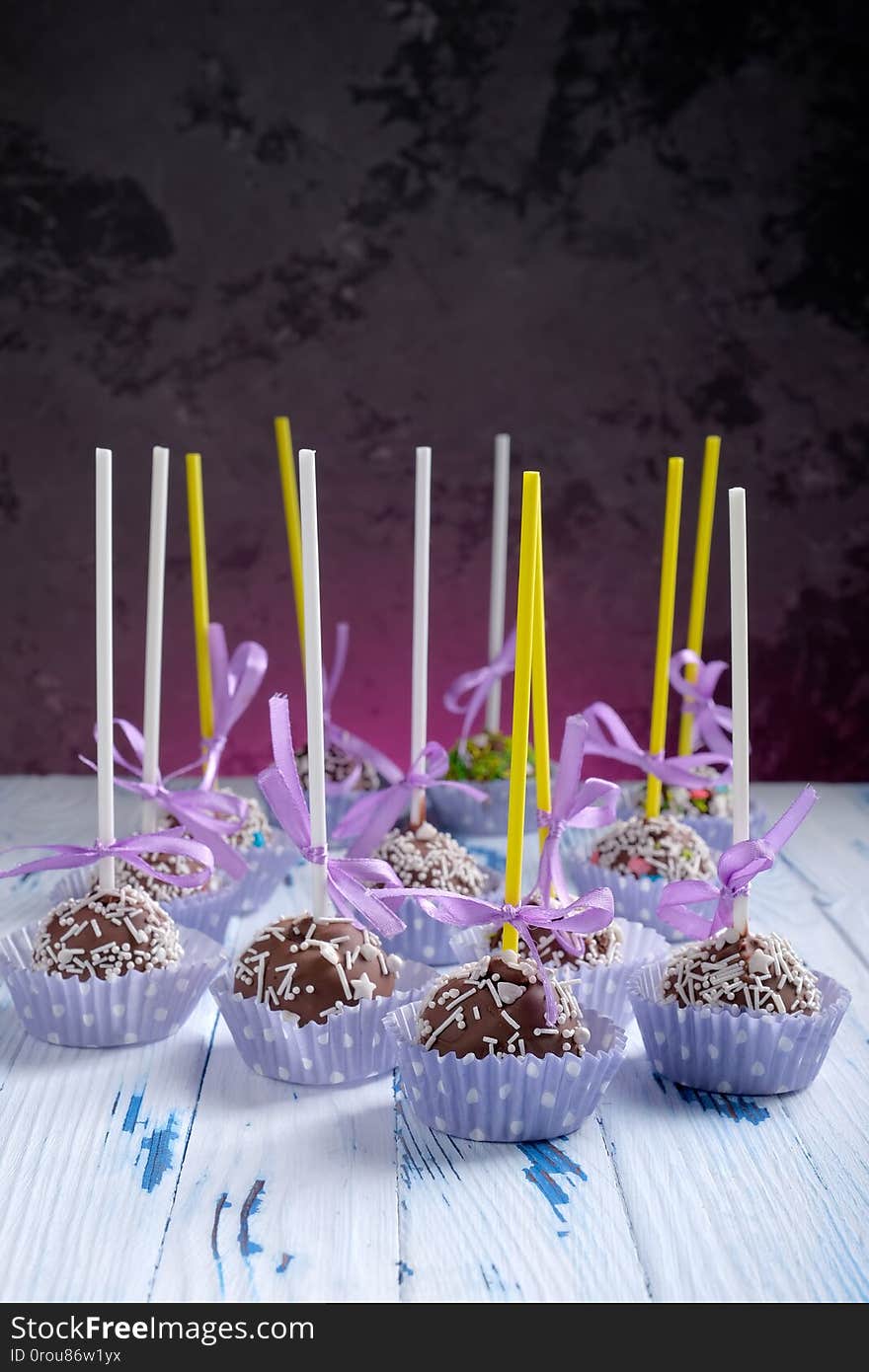 Cake pops coated chocolate with sprinkling on wooden table table on dark background with copy space for text