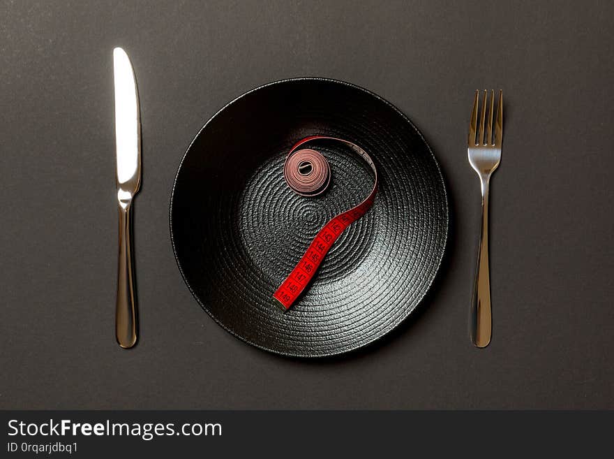 Fork and plate with measuring tape on color background. Diet concept.