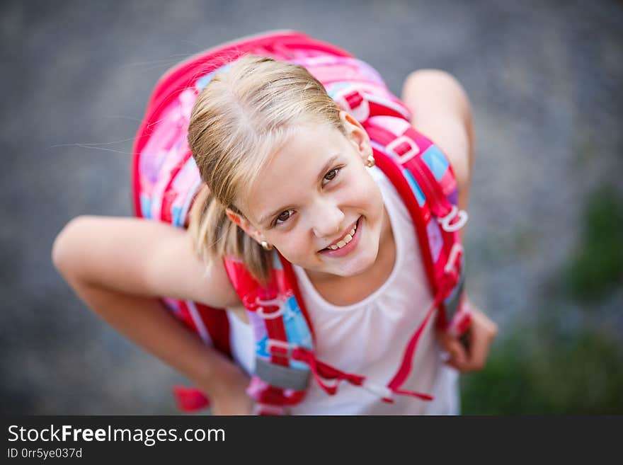 Cute little girl going home from school, looking well before crossing the street