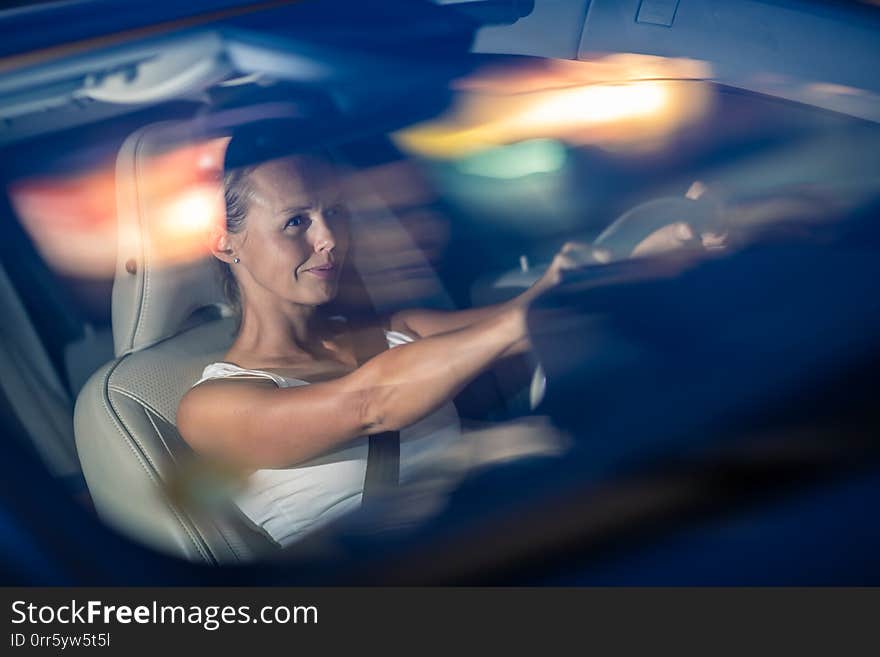 Young female driver driving her car at night color toned image; shallow DOF