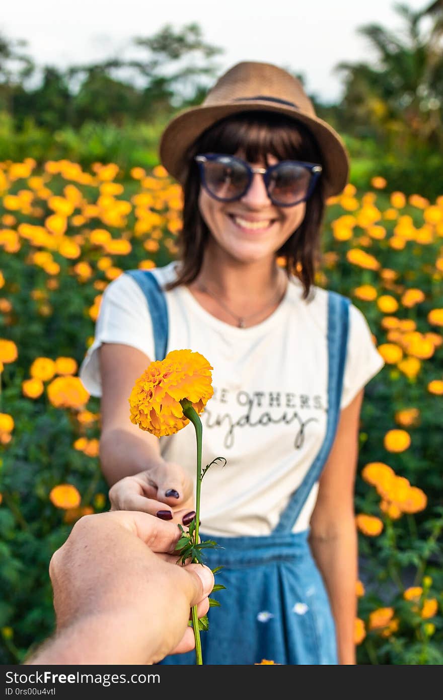 Man gifting a marigold flower to girl on a marigold field. Man hand with yellow flower. Bali island.