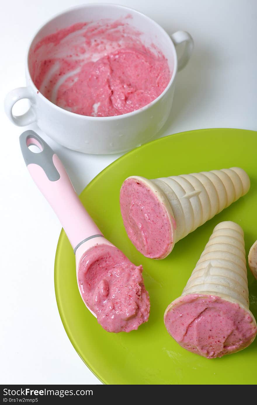 Homemade strawberry and banana ice cream. In edible horns on a plate.