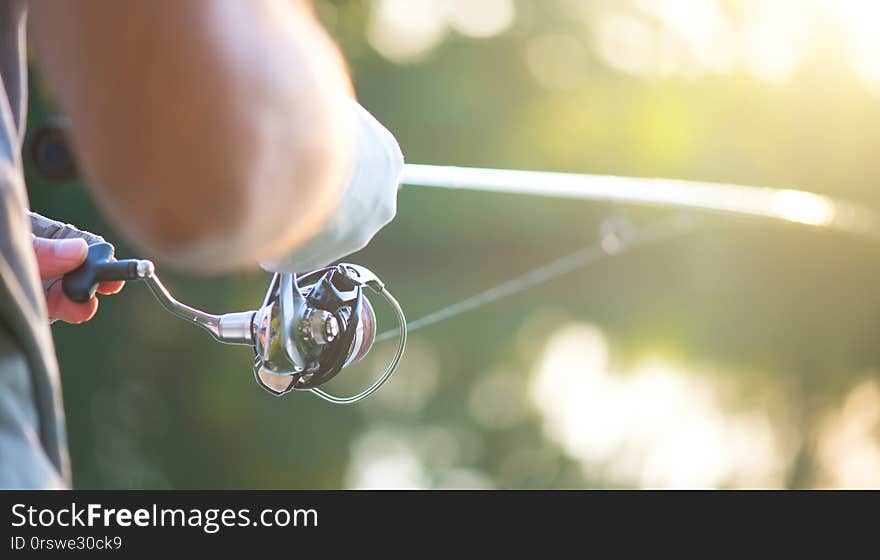 River fishing. Fisherman with a fishing rod on the river bank. Spinning. Fisher man catches a fish