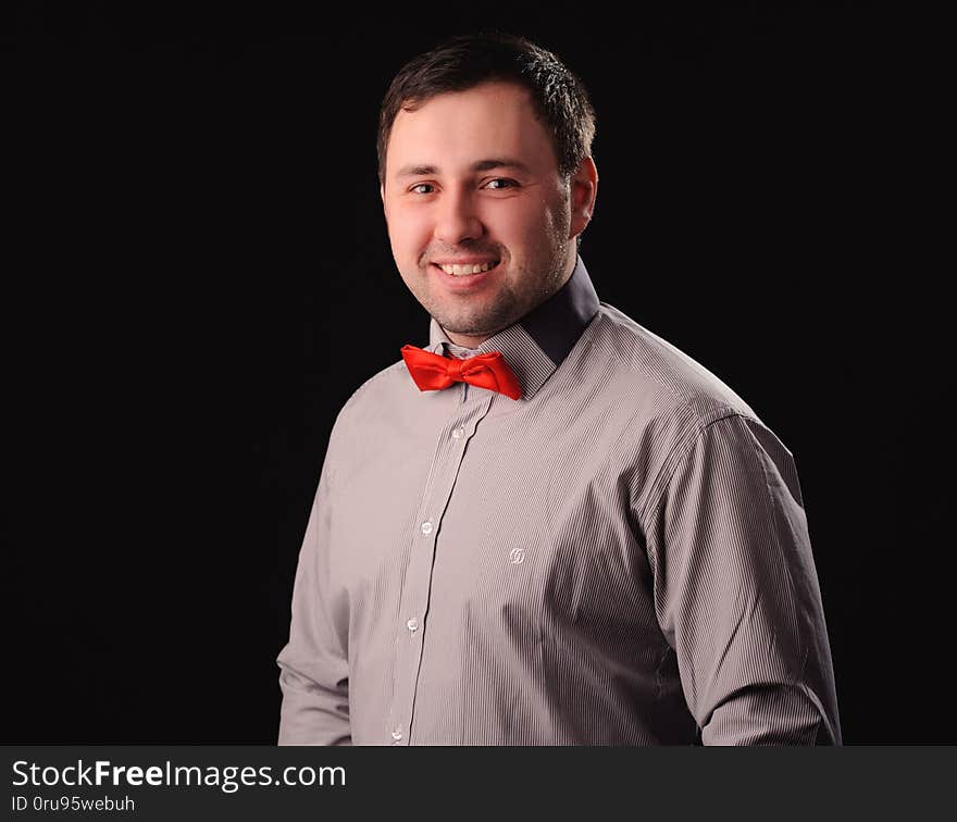 smiling man with red butterfly tie over black background, adult, beard, beauty, bow, bowtie, brown, business, ceremony, classic, closeup, clothes, clothing, dinner, dress, elegance, elegant, evening, face, fashion, garment, guy, happy, hipster, holiday, jacket, luxury, male, modern, object, person, portrait, retro, shirt, smile, style, suit, symbol, textile, traditional, uniform, waiter, well, white, young