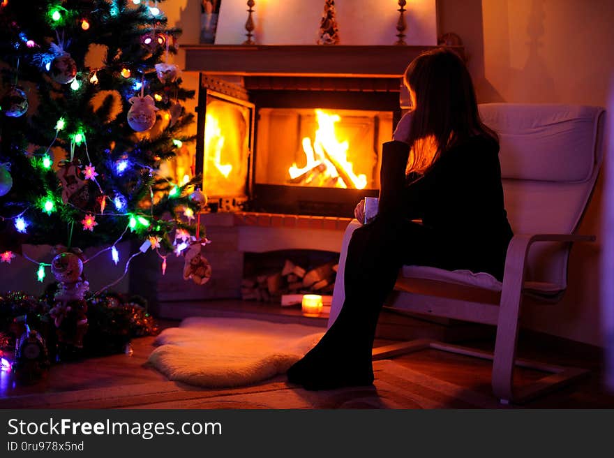 Portrait of pretty woman near fireplace, winter, home, warm, cozy, sitting, cold, tea, people, girl, evening, young, blanket, room, female, reading, house, night, family, relax, person, christmas. Portrait of pretty woman near fireplace, winter, home, warm, cozy, sitting, cold, tea, people, girl, evening, young, blanket, room, female, reading, house, night, family, relax, person, christmas