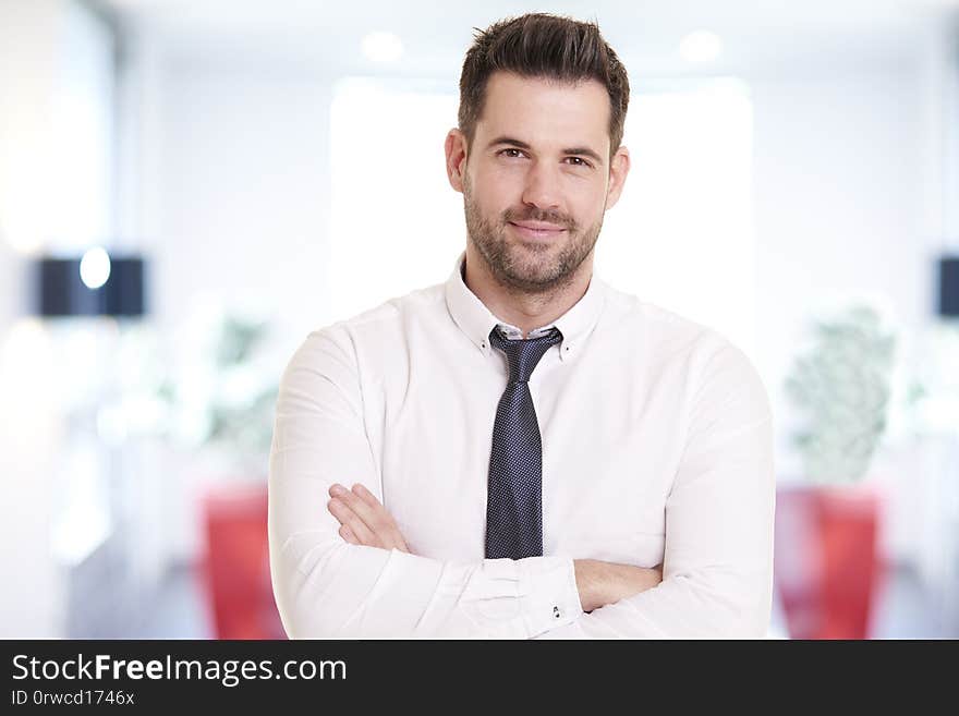 Portrait shot of smiling businessman wearing shirt and tie while standing in the office and smiling. Portrait shot of smiling businessman wearing shirt and tie while standing in the office and smiling