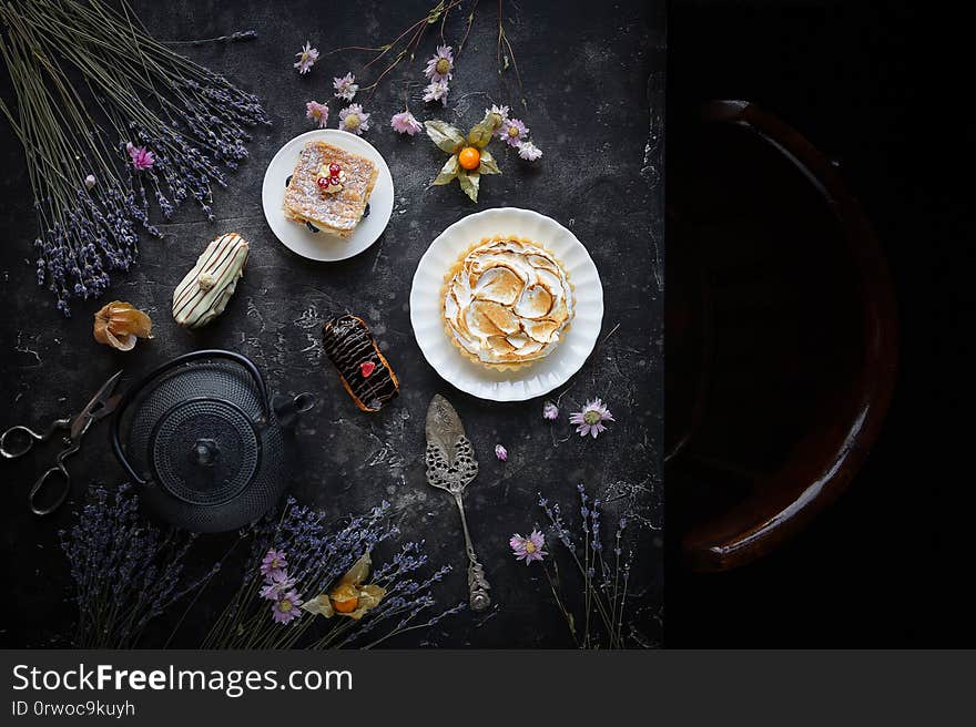 Tea and sweets on a dark background, Mille-feuille, Eclairs, Tart, Decorative with flowers, Top view, Vintage