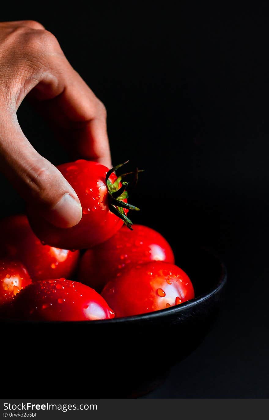 Hand hoilding Fresh red tomato in wooden cup healthy food and vegetable concept on black