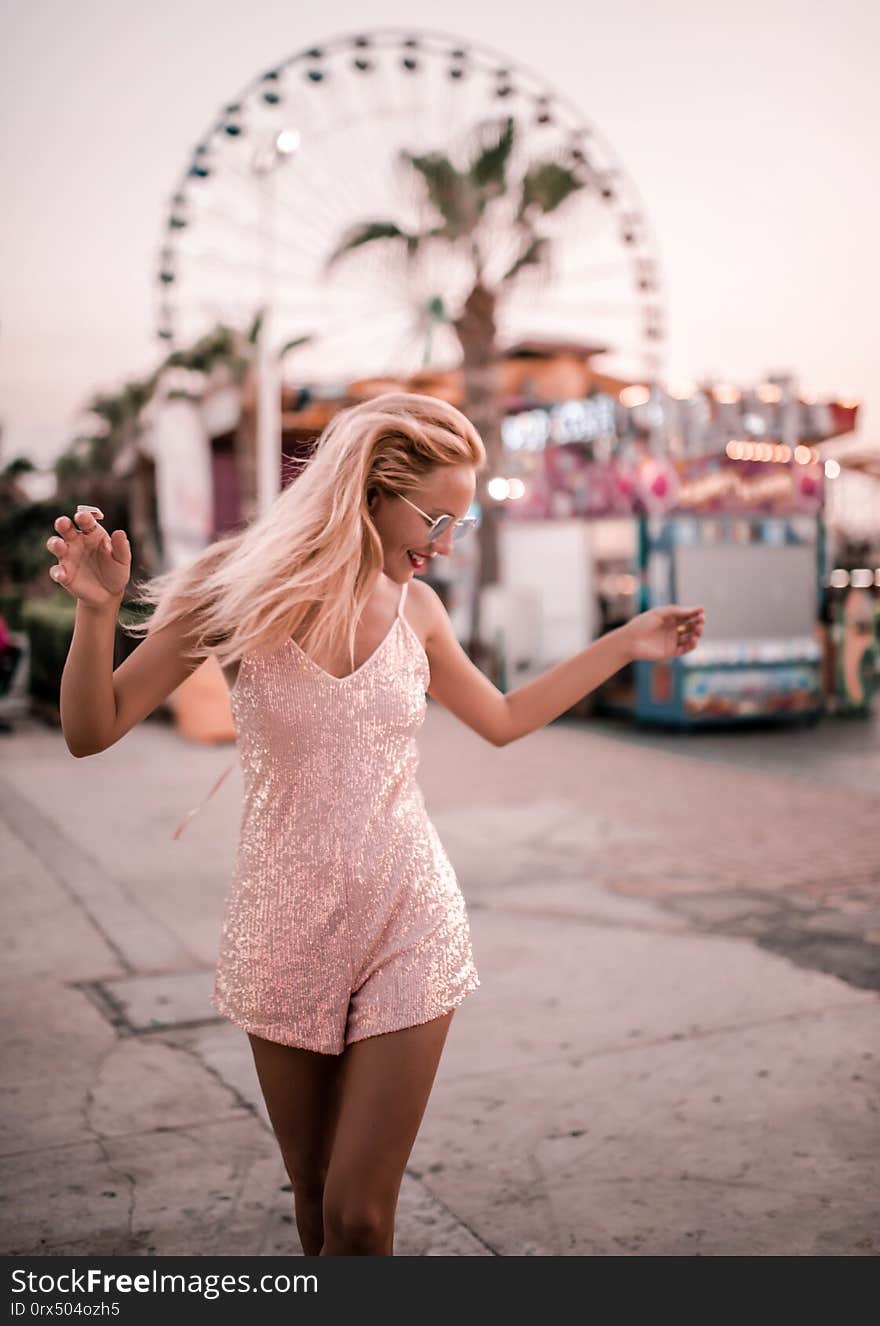 Beautiful hipster girl happy posing at the Ferris wheel near Agia Napa amusement park carousel