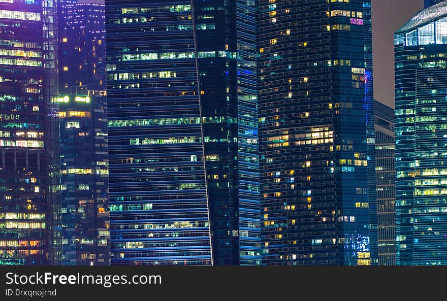 Pattern of office buildings windows illuminated at night. Lighting with Glass architecture facade design with reflection in urban