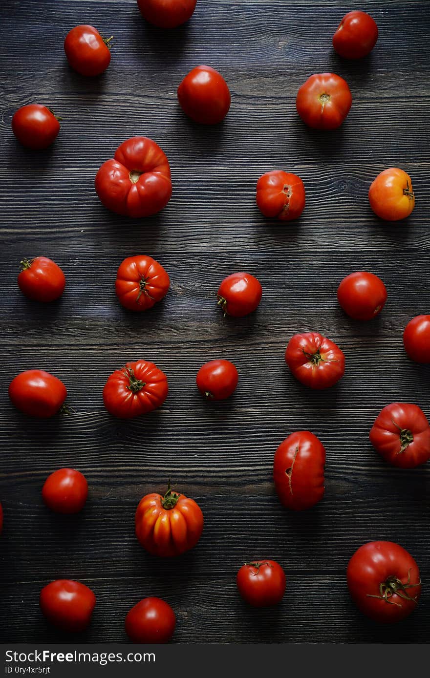 Tomatoes on the old table. Tomatoes pattern. Top view of fresh vegetable on a dark wooden background. Red Food background. Vertical composition isolated on a old rustic wooden surface. Tomatoes on the old table. Tomatoes pattern. Top view of fresh vegetable on a dark wooden background. Red Food background. Vertical composition isolated on a old rustic wooden surface