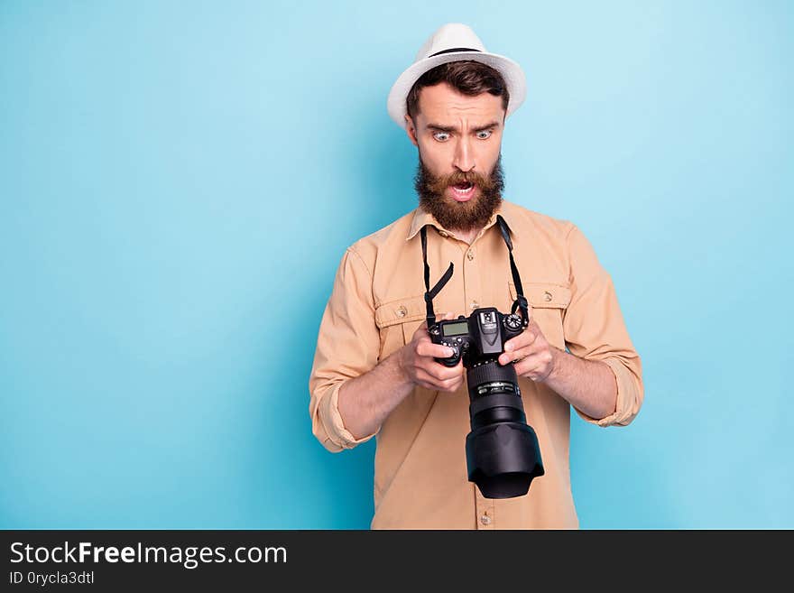 Portrait of impressed person holding camera screaming unbelievable, wearing brown t-shirt  over blue background